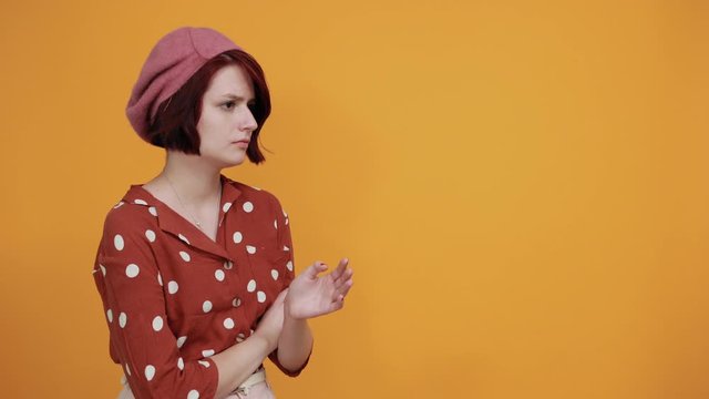 Beautiful brunette caucasian young lady wearing pretty red shirt with polka dot making unimportant and doubts gesture while lifting the shoulders on isolated yellow background
