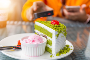 Green tea cake and strawberry ice cream scoop with blurred background, selective focus