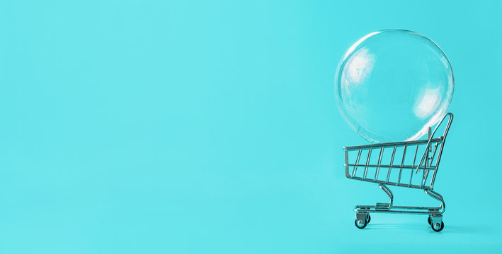 Shopping Cart With Soap Bubble On Bright Blue Background. Ephemeral Happiness From Shopping, Shopaholism, Consumerism Concept. Shopping Concept, Minimalist Creative Layout, Copy Space For Text. Banner