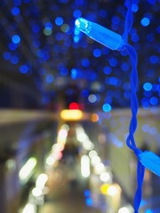 Christmas theme with blue lights. Blurred image of prospekt in the dark. Bokeh of streetlights at nightscape. Abstract background. Soft focus.