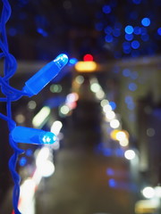 Christmas theme with blue garland. Blurred image of prospekt in the dark. Bokeh of streetlights at nightscape. Abstract background. Soft focus.