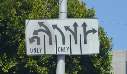 Traffic sign in New York City with a confusing number of directional arrows.