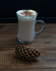 cappuccino on a wooden brown table with a pine cone