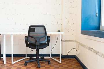 Loft style office with white brick walls and concrete columns. There is a meeting area with a large white table with black chairs