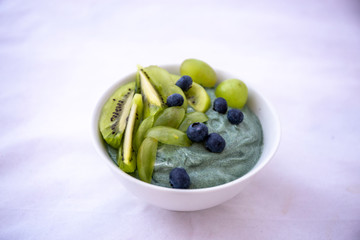 Spirulina smoothie bowl with green fruit and blue berry
