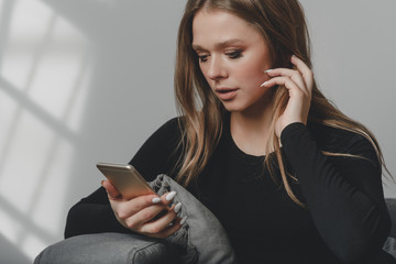 Portrait of a young sad crying girl with a smartphone in her hand.