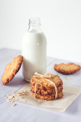 Oatmeal cookies and a glass bottle with milk on a light background, healthy nutrition. Breakfast or evening snack