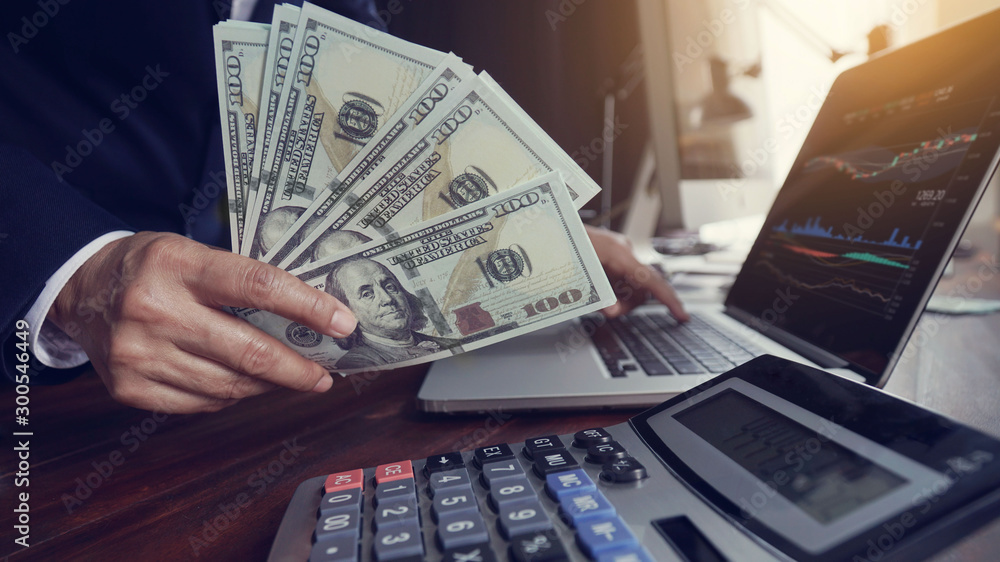 Aufkleber hand of businessman holding banknote and analyzing data stock market, currency exchange with using c