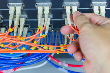 Technician connect fiber cable network to switch port in server room , Concept internet network...
