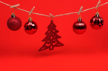 Red Christmas toys balls on a string with clothespins on a red background, preparing for the new year and Christmas