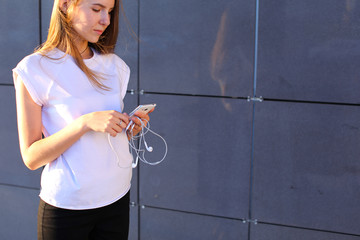 One young female woman unravels headphones for listening to music, talk on Skype, holds in hands...