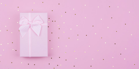 Gift or present box and stars confetti on pink background. Flat lay composition for birthday New Year, copy spase