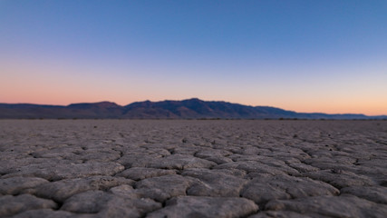 Fototapeta na wymiar Sunrise in a desert. View of a cracked surface of Alvord desert with Steens mountains in the background
