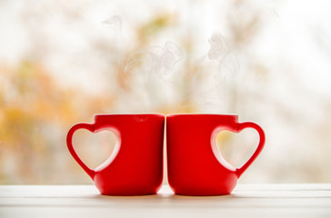 two heart shaped mugs with tea on natural background