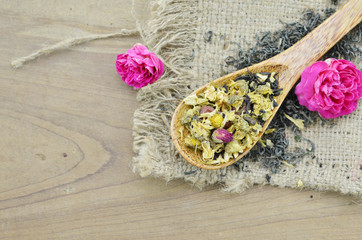 Assortment of dry flower tea in spoons on wooden background