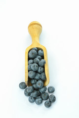 blueberries in a wooden spoon on a white background