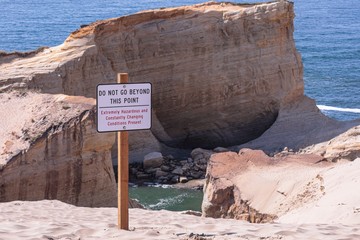 Posted sign on a edge of a cliff of Cape Kiwanda read 