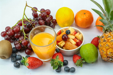 fruit juice with fresh fruits around the glass on a white background