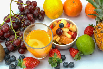 fruit juice with fresh fruits around the glass on a white background