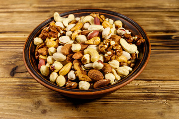 Mixed nuts on wooden table. Walnuts, pistachio, almond, peanut, cashew, hazelnut in ceramic bowl. Healthy eating concept