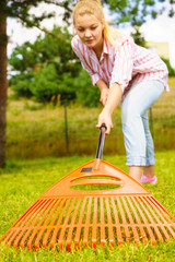 Woman using rake to clean up garden lawn