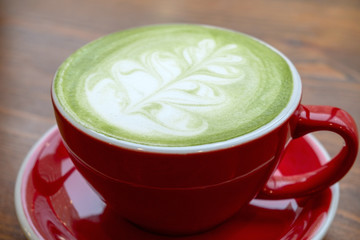 close up   match tea latte with a latte art in red ceramic mug in a coffee