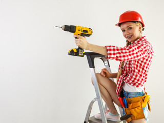 Woman using drill on ladder