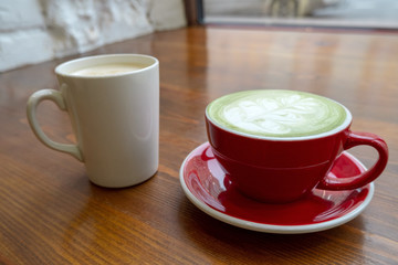 couple of cups with coffee and matcha tea on a vintage wooden table in a coffee shop