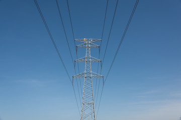 A large metal high voltage transmission tower close-up in a cloudless sky