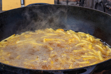 French fries cooking in a deep cast iron pan filled with oil