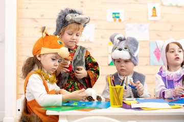 Children cutting out scissors paper in preschool or daycare. Kids weared funny costumes