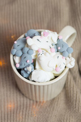 Cocoa with marshmallow in gray and white mouse or rat shape in cup with fairy lights christmas picture. Vertical.