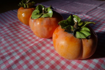 赤いギンガムチェックの布の上の柿