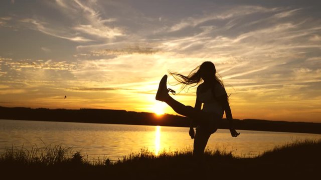 Happy girl with long hair is dancing at sunset on the beach and laughing. Free and cheerful woman. Slow motion.