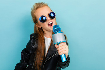 photo of cheerful stylish schoolgirl with a microphone on a blue background