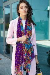 Medium full shot of a brunette lady with a black handbag wearing a pink coat in modern urban...
