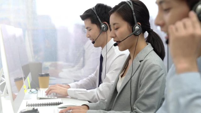 Asian businesswoman wearing headphone working in call center office with team  