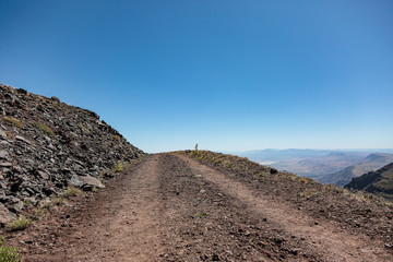 Gravel road on a side of a cliff leading into the sky, Steens Mountains