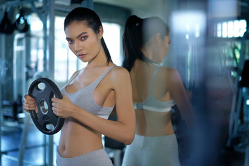Fototapeta na wymiar Asian sporty doing exercise with disassembled barbell or dumbbell at fitness gym. Woman taking weight loss for slim. Healthy sport cardio strong. Fitness muscular body.