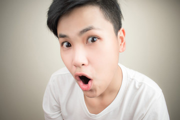 Shocked, Asian faces wearing white shirts on a gray background.