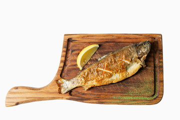 Fried fish with lemon served on a wooden cutting board. Isolated over white background.
