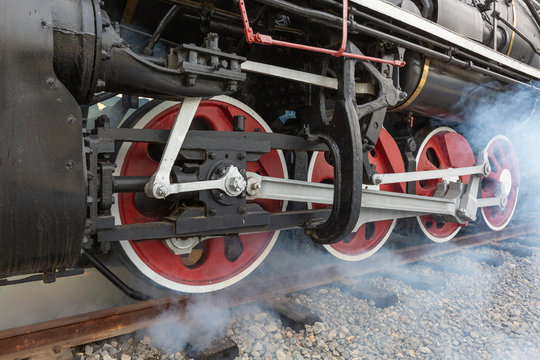 Close-up of a driving wheel of an old-fashioned steamed red-black painted vintage steam train