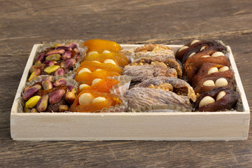 Sweet natural eastern delight with dried apricots, figs, walnuts, pistachios and almonds on a rustic wooden background with copy space.