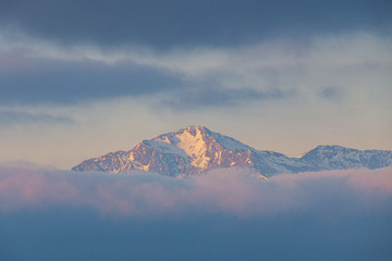 Fototapeta na wymiar Far distant snowy mountain top during sunrise