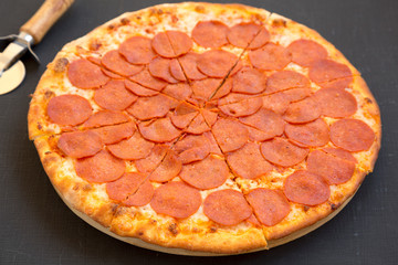 Delicious Pepperoni pizza over black background, low angle view. Close-up.
