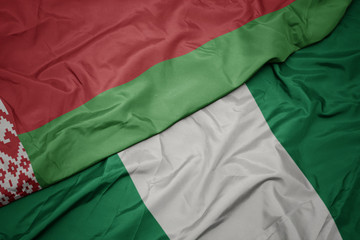 Obraz premium waving colorful flag of nigeria and national flag of belarus.