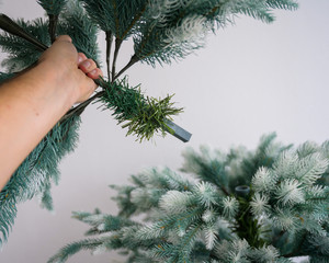 A man mounts a composite reusable spruce for the new year. Decoration for the holiday. Protection...