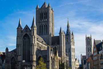 Fototapeta na wymiar Facade of Saint Nicholas' Church (Sint-Niklaaskerk) with the clock tower of Belfry of Ghent (Het Belfort) and Saint Bavo Cathedral (Sint-Baafskathedraal) at the background, in Ghent, Belgium