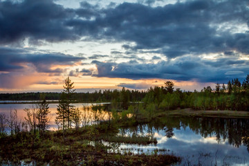 Fototapeta na wymiar Summer Night landscape in the north of the Kola Peninsula in Russia. White nights, lakes, forests and beautiful clouds reflected in the water