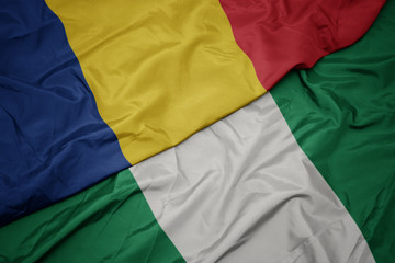 Obraz premium waving colorful flag of nigeria and national flag of romania.